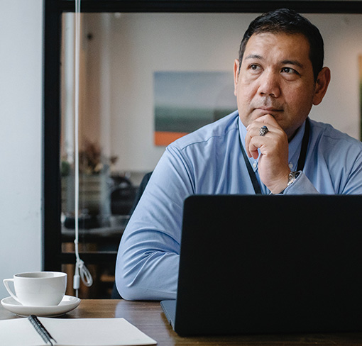 Person working on laptop, looking away from screen in an office.